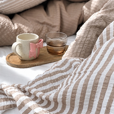 ada taupe i rodet seng med kaffekop